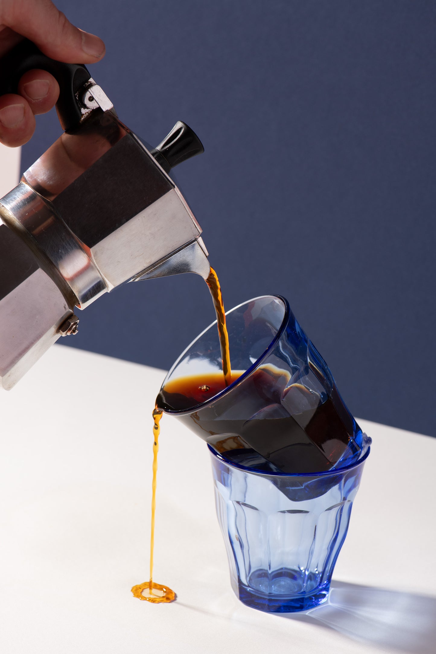 Cafetière italienne verse de la chicorée dans une tasse bleue. La chicorée déborde de la tasse.