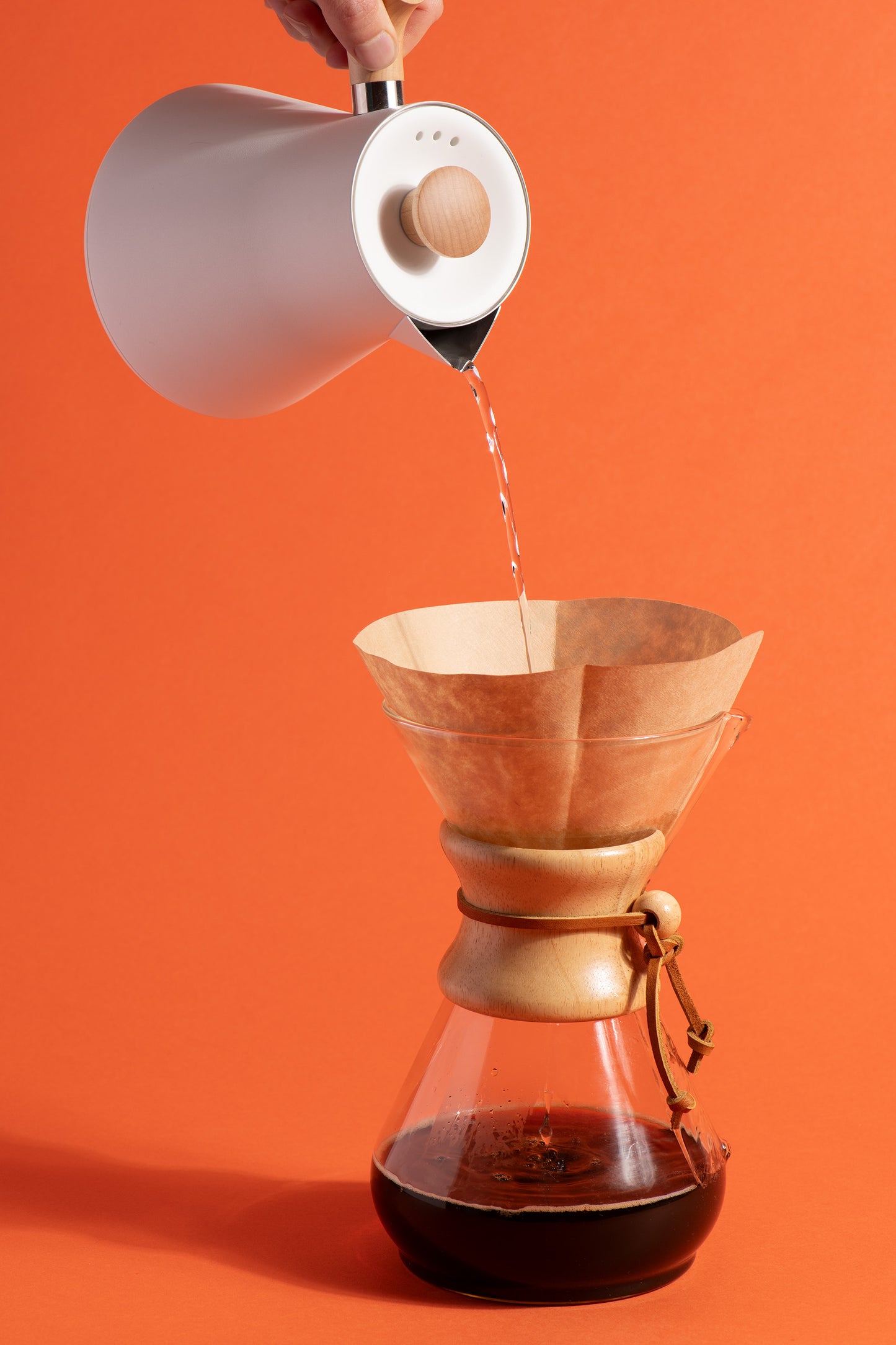 Une bouilloire verse de l'eau chaude dans une cafetière filtre pour infuser de la chicorée Chico