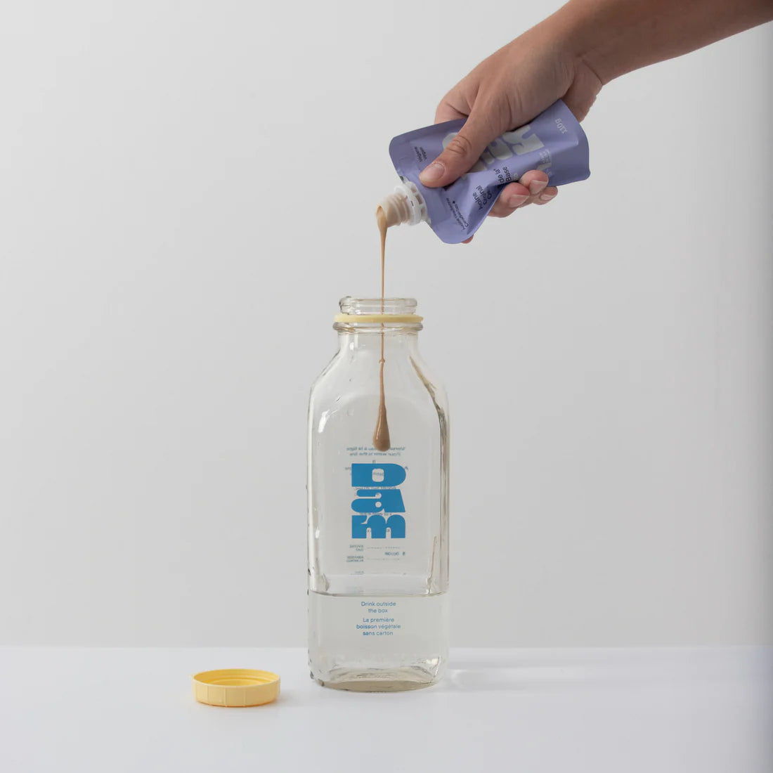 Comment préparer le lait d'avoine Dam. On verse le concentré d'avoine dans la bouteille.