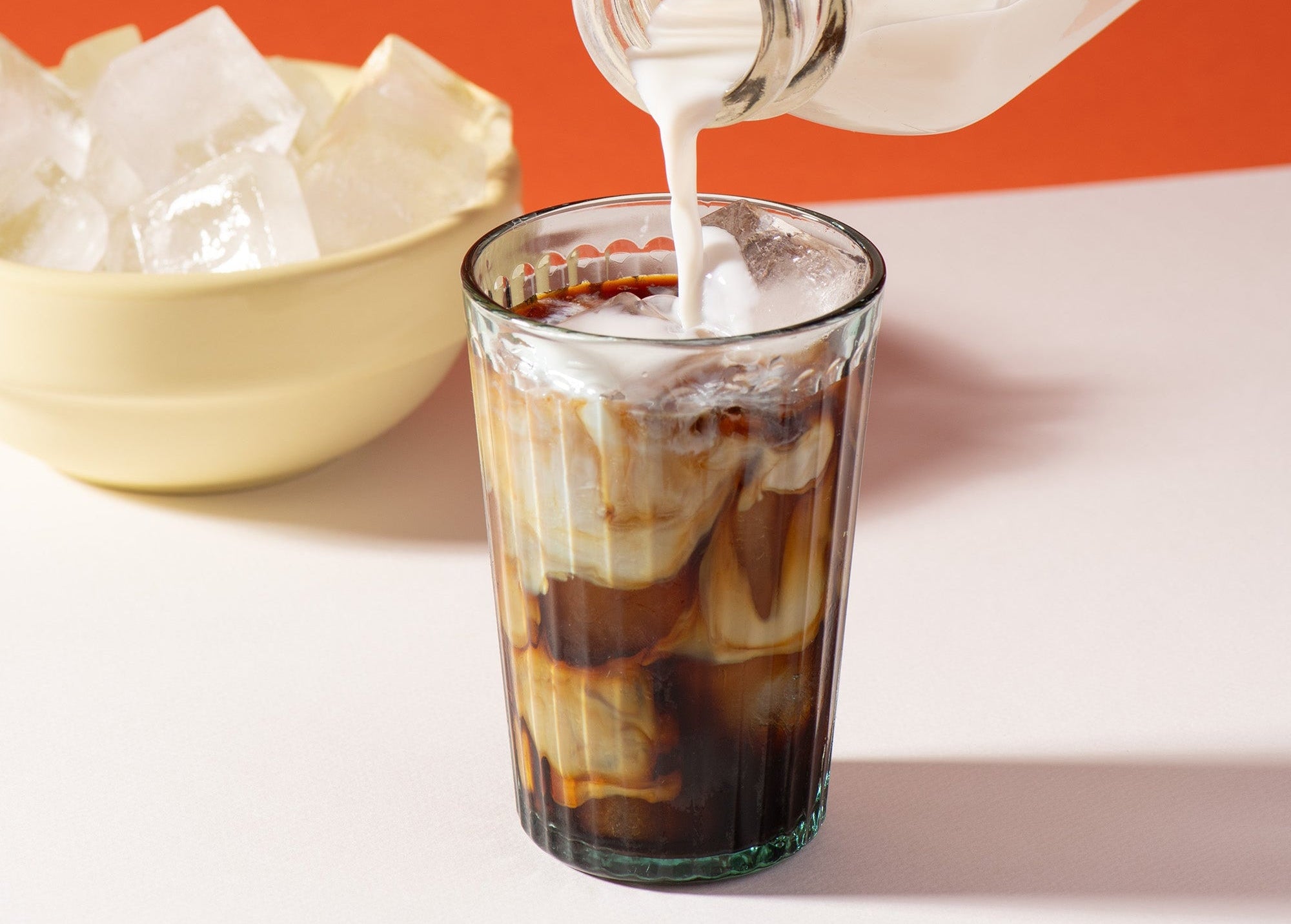 Lait qui se verse dans une tasse de chicorée Chico pour faire un Café Glacé