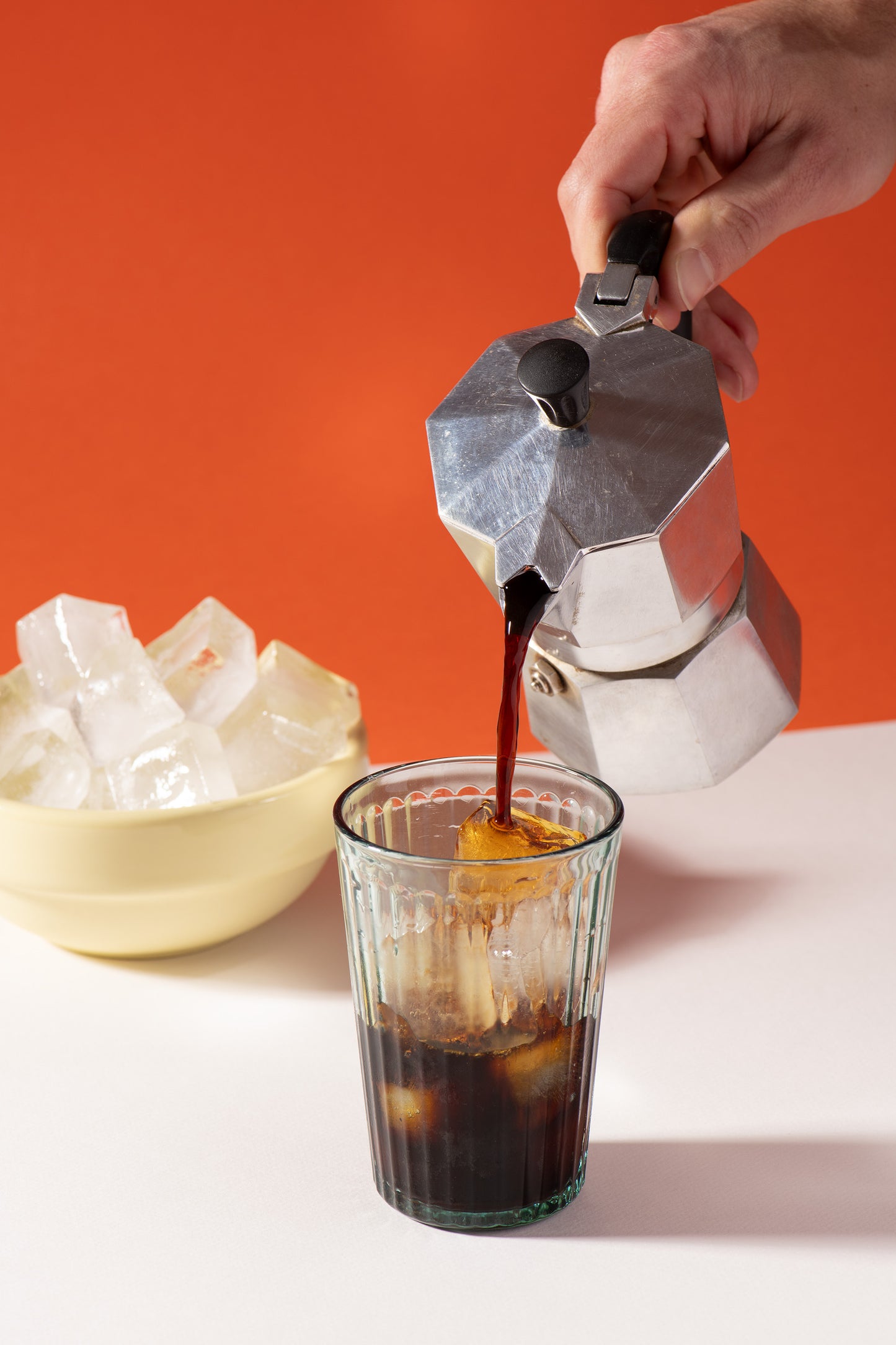Cafetière italienne qui verse de la chicorée dans une verre rempli de glacon pour faire un chicorée glacé