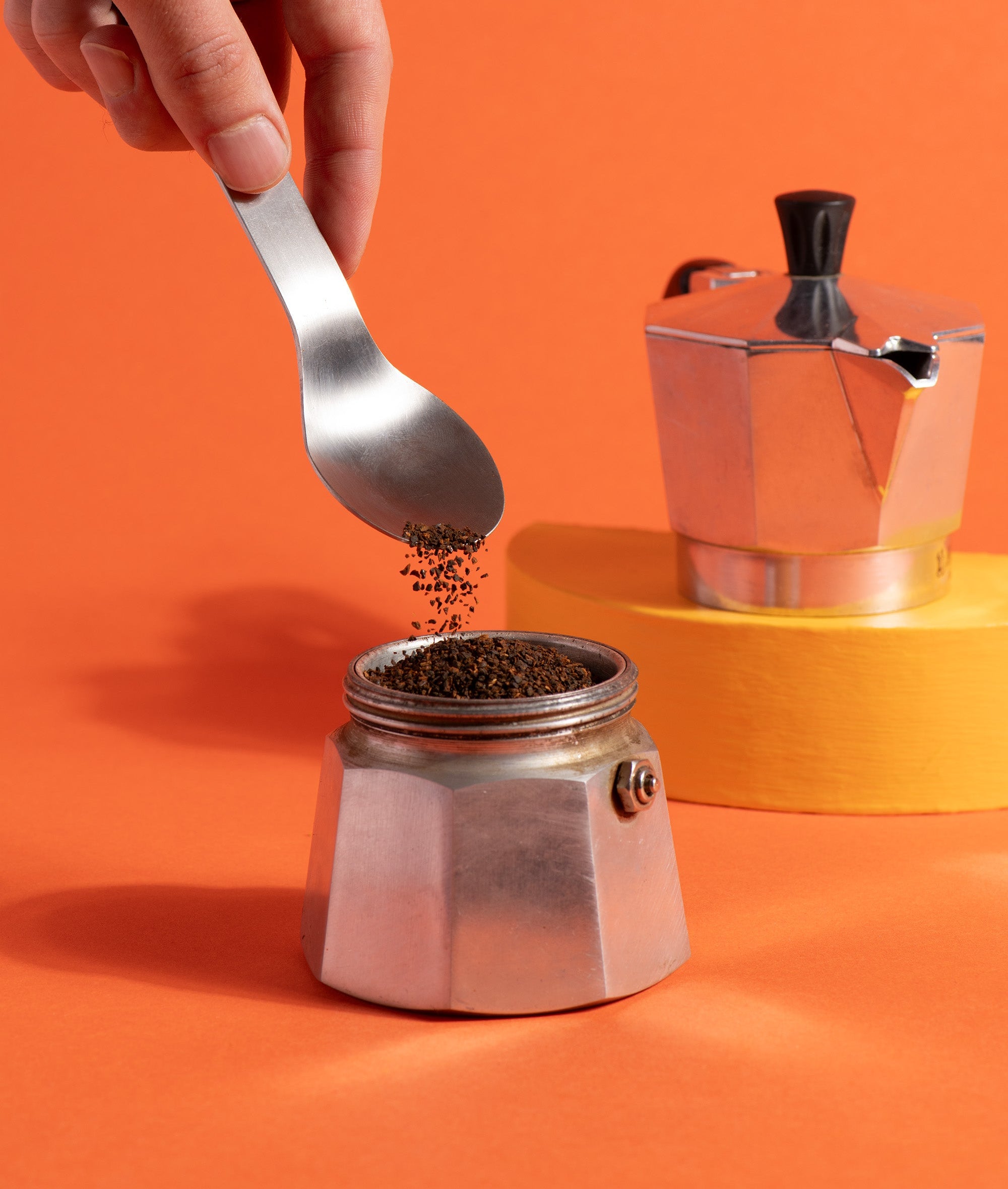 une cuillère verse de la chicorée moulue Chico dans le filtre d'une cafetière italienne